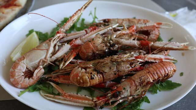 Grilled langoustines served with fresh arugula and lemon in a restaurant offering a flavorful seafood dish for travelers enjoying local cuisine during summer vacation