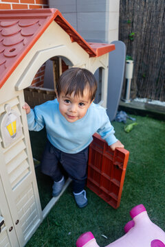 A toddler white boy steps out of a plastic play structure