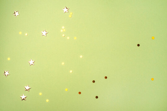 Gold confetti on green background. Flat lay, top view