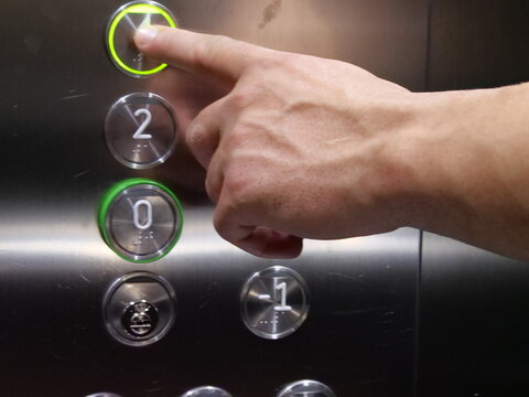Hand Pressing an Elevator Button with Green Light