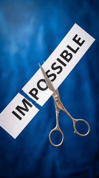 Scissors cutting the word "IMPOSSIBLE" in half, turning it into "POSSIBLE", symbolizing overcoming challenges and achieving goals