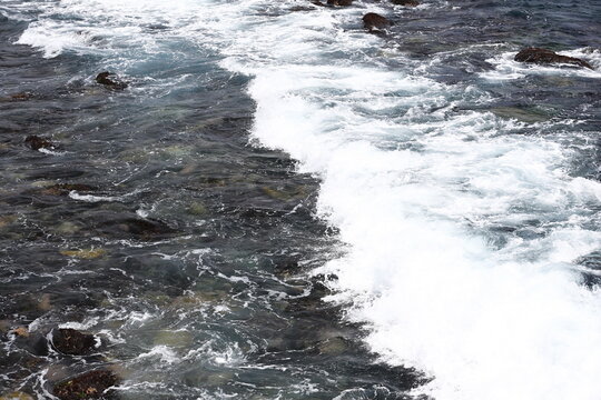 Powerful Ocean Waves Crash Across Dark Coastal Rocks.