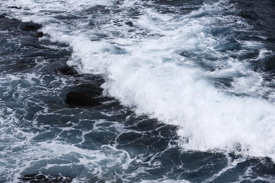 Powerful Ocean Waves Crash Across Dark Coastal Rocks.