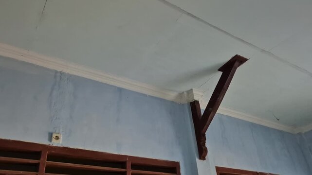 Low angle shot of wooden ceiling support brackets on light blue interior wall