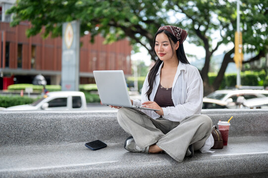 Young Asian Woman Working on Laptop Outdoors in Public Space