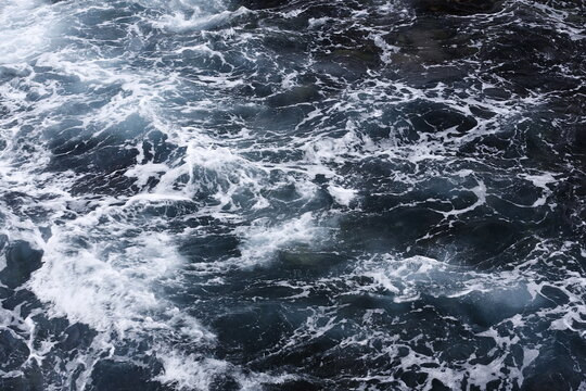 Sea Foam Swirls Across Dark Coastal Rocks.