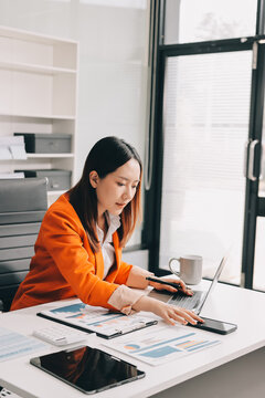 Office Discomfort: A female office worker in a red shirt experiences neck pain while working on her laptop, surrounded by office supplies and a calculator, indicating a stressful work environment.