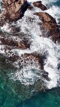 Aerial View of Ocean Waves Crashing Against Coastal Rocks
