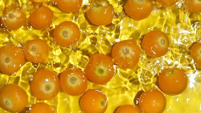 Fresh physalis berries in water splash for refreshing food concept, slow motion.