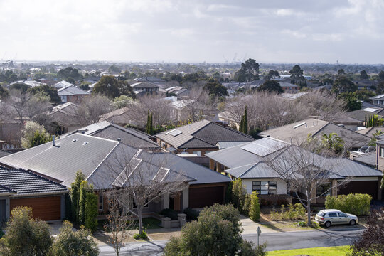 Aerial view of a suburban residential neighborhood in Melbourne, Australia. Modern single-family homes and winter trees with bare branches along quiet residential roads