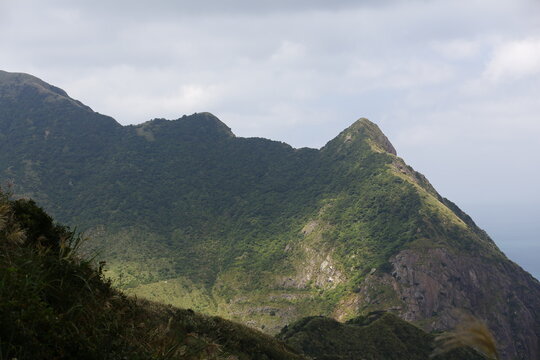 Sunlight Illuminates a Rugged Green Mountain Ridge.