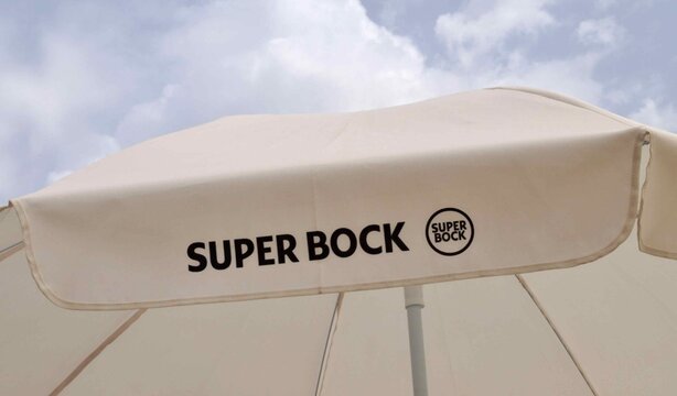 Super Bock branded beach umbrella under summer sky