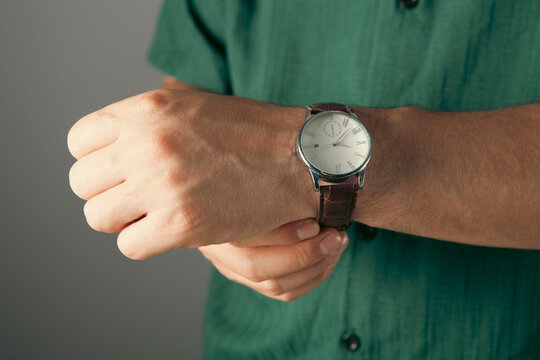 Men's wrist watch in the hands of men on a gray background