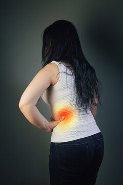 Woman suffering from back pain on gray background. Health care concept.