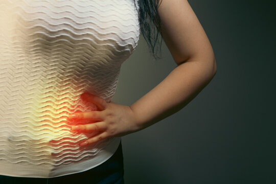 Woman suffering from back pain on gray background. Health care concept.