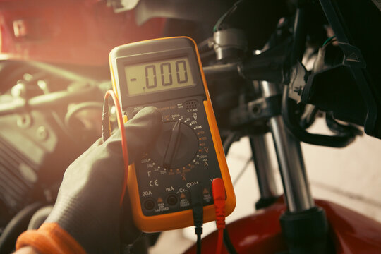 mechanic working with multimeter on motorcycle, car maintenance concept