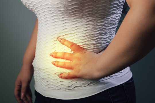 Woman suffering from back pain on gray background. Health care concept.