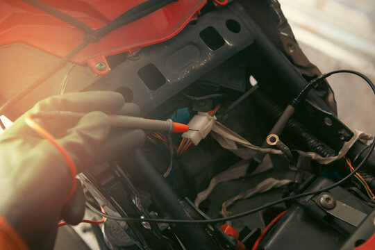 mechanic working with multimeter on motorcycle, car maintenance concept