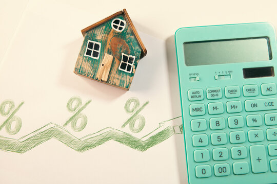 House model, calculator and percentage sign on white paper background. Real estate concept
