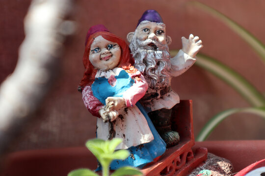 Dettaglio in primo piano di una coppia di vecchie statuine da giardino in miniatura raffiguranti gnomi o personaggi folcloristici colorati posizionati all'esterno