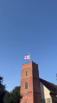 English Church Tower with St George&rsquo;s Flag Against Clear Blue Sky
