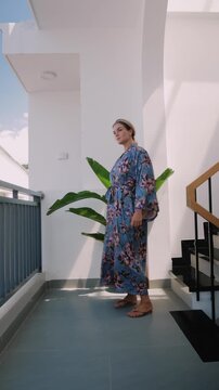 Elegant woman wearing luxury kimono robe in modern tropical home.