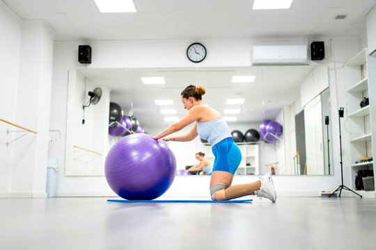 Woman with disability exercising in gym, using stability ball for balance and strength