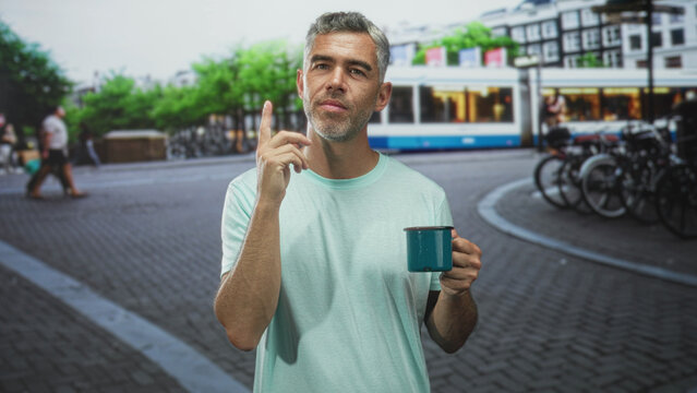 Man holds teal mug and points finger upward on a city street with tram and bicycles; curiosity insight.