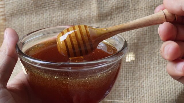 Hand dripping honey from honey dipper