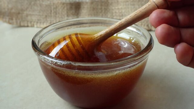 Hand dripping honey from honey dipper
