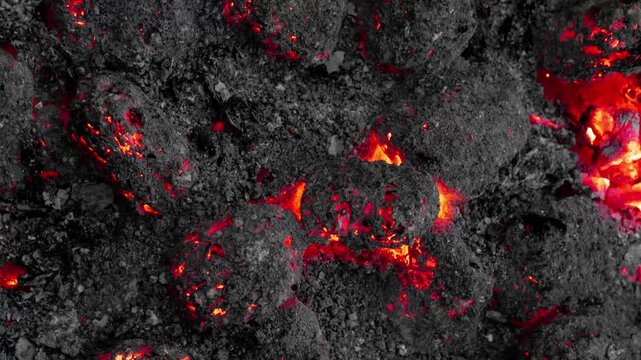 Close-up Macro View of Glowing Hot Coals and Ash with Fiery Red Embers fire. Rocky surface abstract fire planet concept. Abstract Molten Lava Sphere with Glowing Cracks.