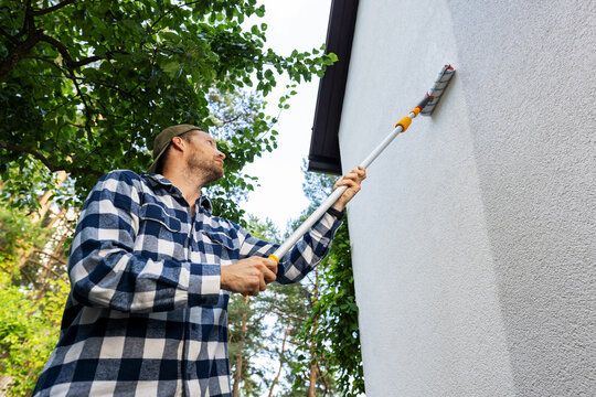 house painter restore paint on building exterior with roller