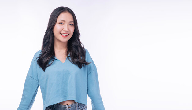 Portrait of a beautiful smiling young Asian woman in casual blue sweater looking at camera isolated on white background with copy space. Happy female student or casual lifestyle concept.