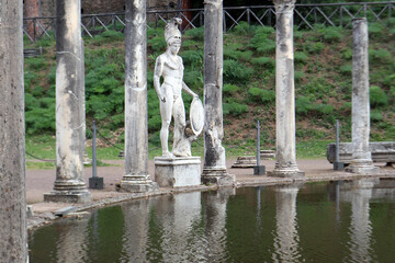 Statua classica del dio Ares tra le antiche colonne corinzie del Canopo a Villa Adriana riflesse sulla superficie della vasca, Tivoli, Italia © Ilarialapreziosa