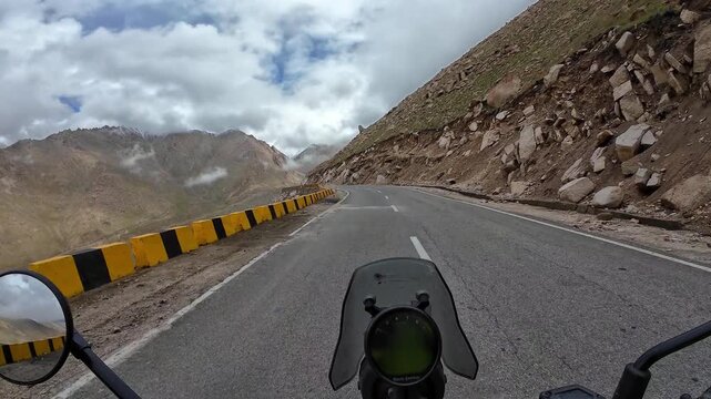 Ladakh, India: Time wrap point of view footage of motorcycle on  mountain road by rocky hills in Chang La pass, main gateway to Changthang plateau near Leh of Ladakh, India on sunny day