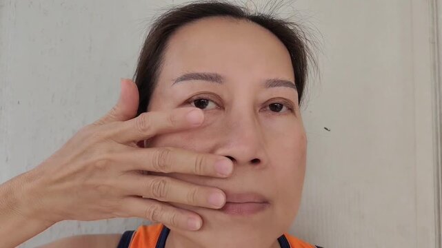Middle aged woman holding the flabbiness adipose sagging skin, Flabby skin and loose beside the mouth, health care and beauty concept.
