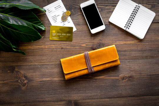Pay restaurant bill. Bill, bank card, wallet, coins on dark wooden table top view