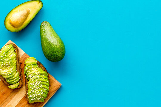 Healthy food. Avocado toast on blue background top view frame copy space
