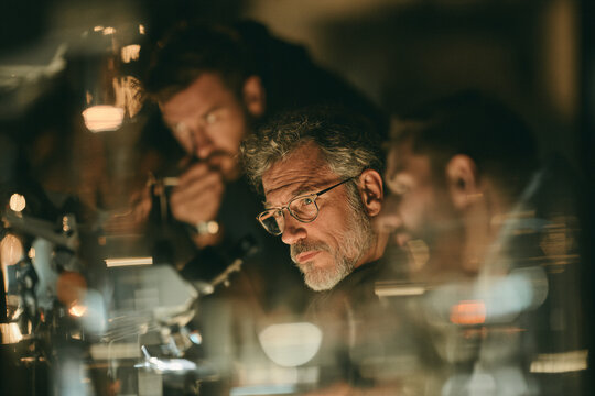 Scientist in glasses among reflections in a warm laboratory