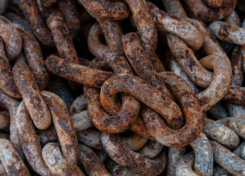 Heavy weathered industrial chains covered in rust create a full frame abstract background texture