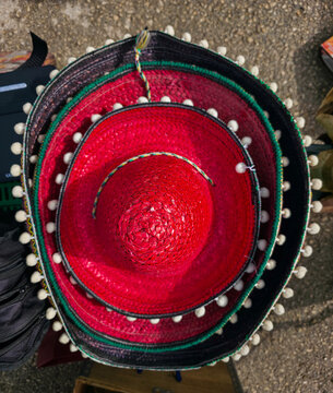 Vibrant red and black sombreros with white pom poms create a festive display in a market setting