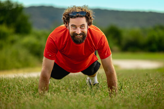 Man doing push-ups on grass outdoors during day