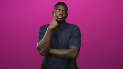 Obraz premium Man with hand to chin and arm crossed, looking up with palm raised and slight shrug in magenta studio; thoughtful uncertainty.