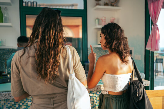 Friends enjoy cafe culture while ordering coffee at an urban shop during a social break in the city