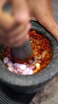 Cooking Thai food video showing traditional Northern Thai Nam Prik Ong preparation. Pounding chili paste in mortar, stir frying with ground pork and diced tomatoes in wok, and serving in a bowl.