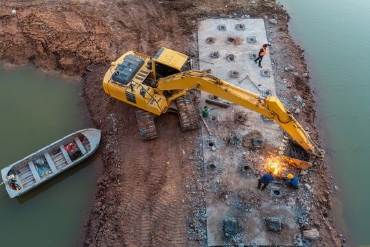 Aerial View of Workers Welding Steel Reinforcement for Bridge Pier Foundation Construction at River Infrastructure Project