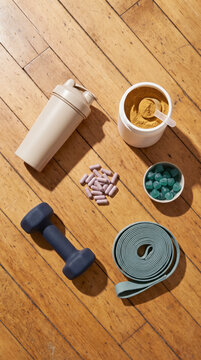 Wooden floor flat lay of protein jar shaker towels and supplements with plant