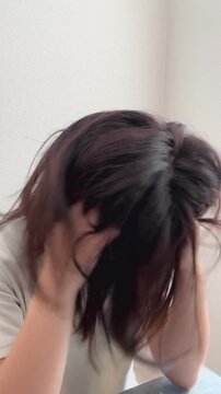俯いて頭を抱える絶望する女性の縦動画