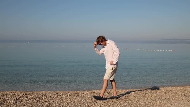 Young man dislikes seaside vacations and walks frustrated along the beach feeling bored and out of place as he struggles to find anything enjoyable to do and wishes to go home