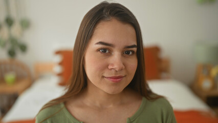 Naklejka premium Woman on bed with exposed shoulder smiles and looks at camera inside building; serenity home comfort.
